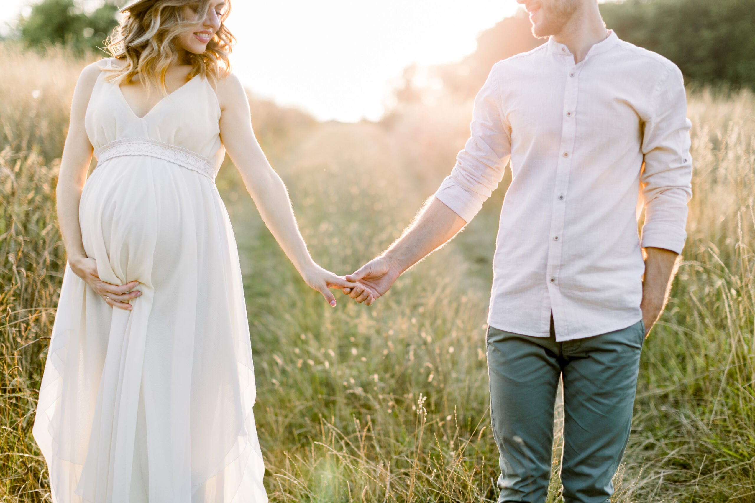 Young,Happy,Romantic,Pregnant,Couple,Walking,In,Wild,Field,In